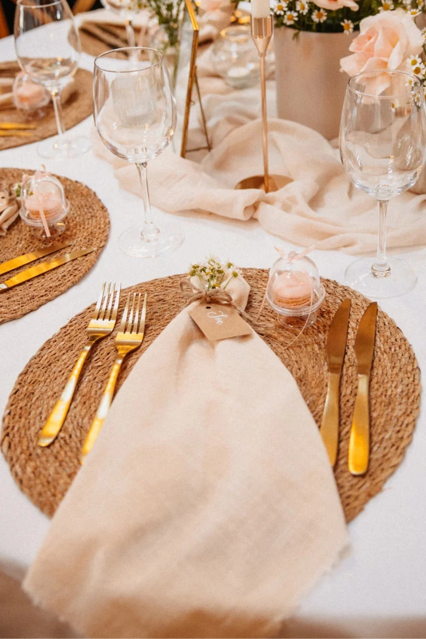 Hochzeitstisch mit Dekoration und Platzssets und Goldbesteck sowie Gastgeschenke