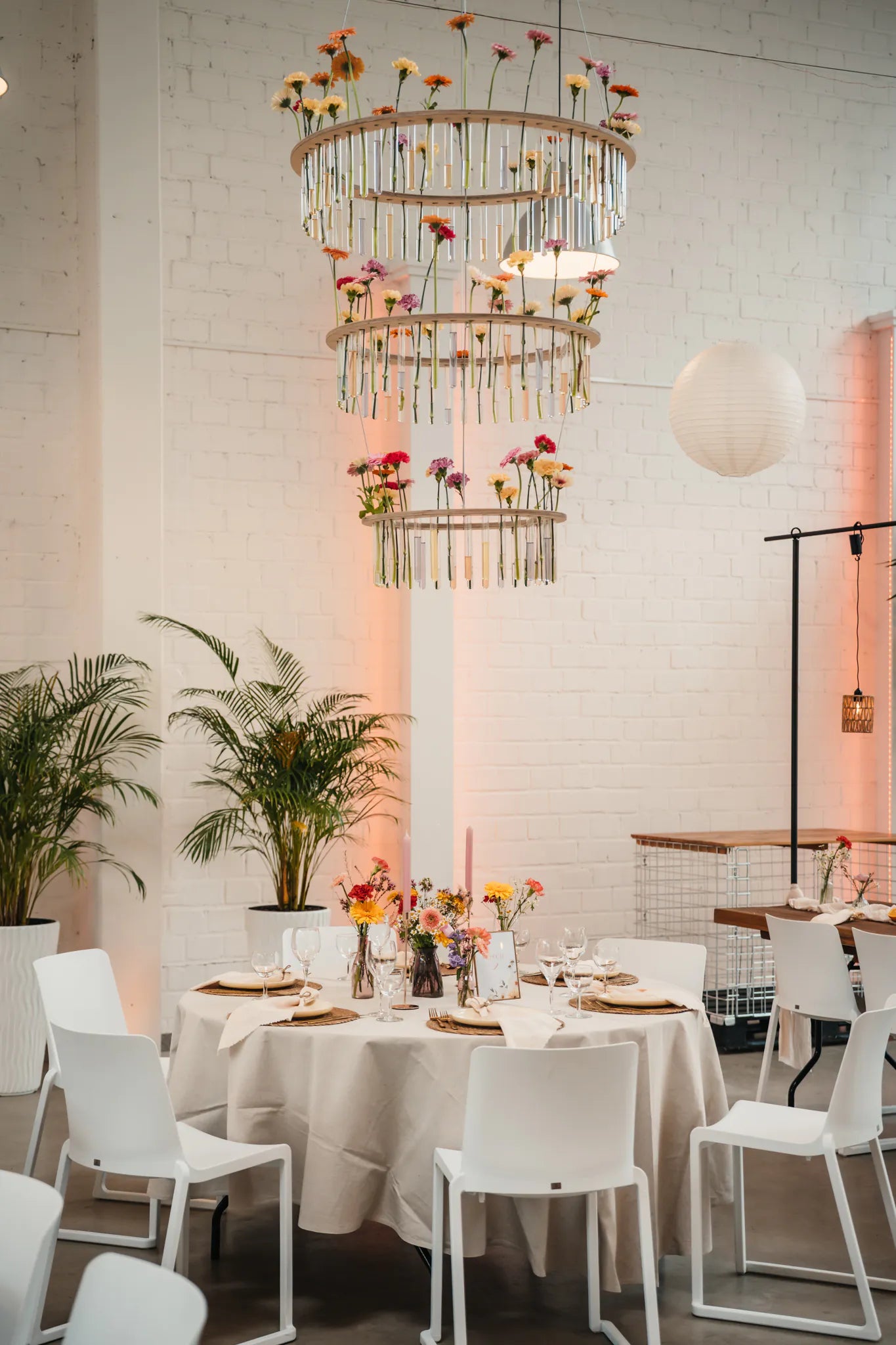 Hochzeitsdeko in Hochzeitslocation mit bunter Blumendeko und haengender floralen Installation