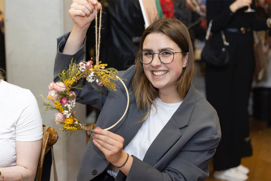 Workshop Teilnehmerin ist glücklich mit selbstgemachtem Blumenkranz bei Teamevent